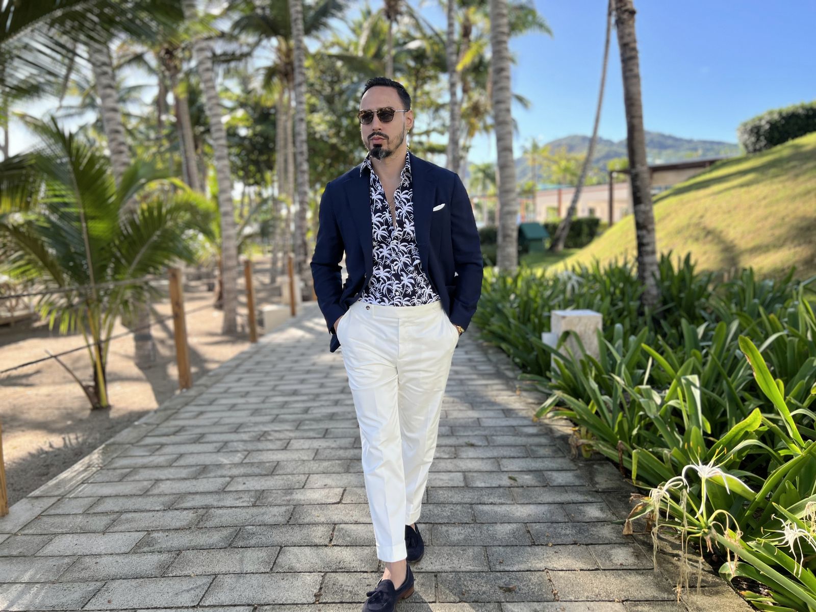 Navy jacket over a patterned shirt with white trousers