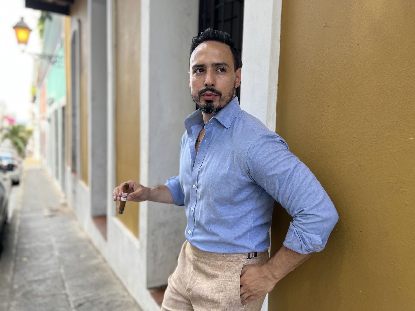 Blue shirt and stone trousers against a yellow wall